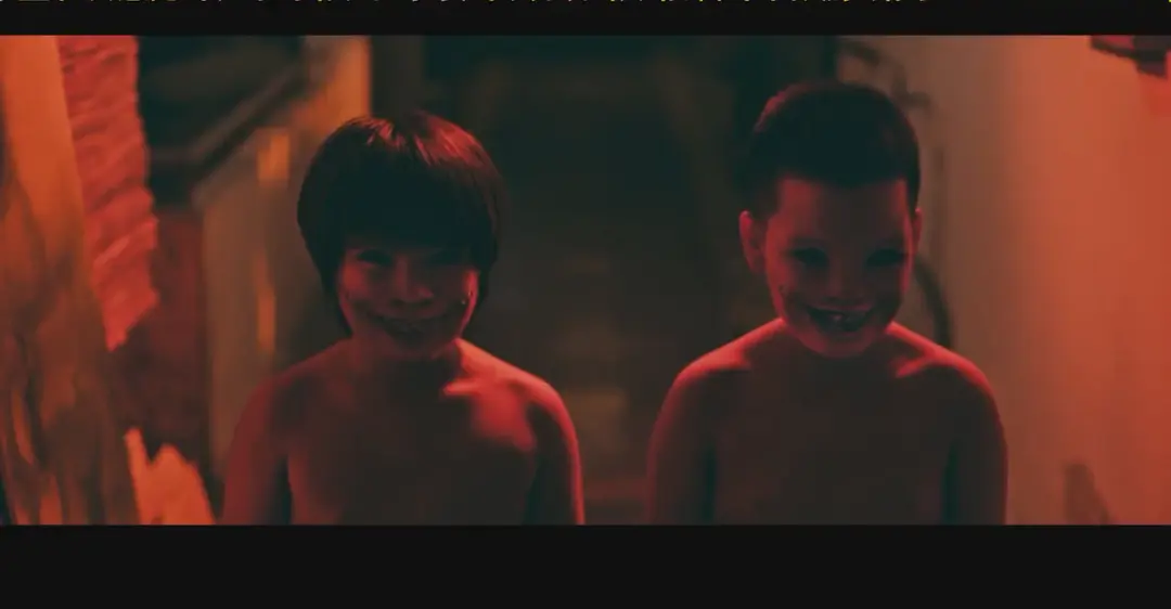 Two creepy - looking children in Chuyện ma gần nhà, under an orange - toned light.