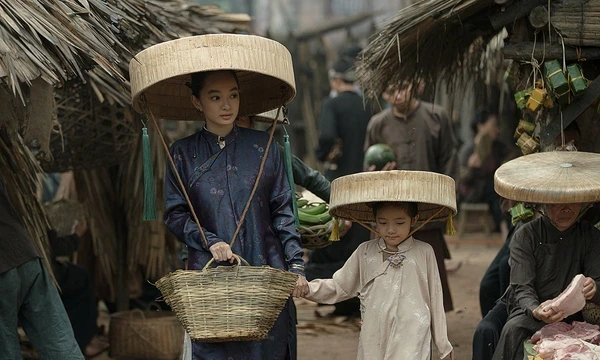In The Last Wife, a woman holding a basket and a child walk in a bustling old - street, both wearing traditional hats.